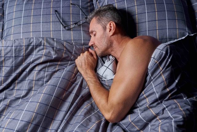 Sleep Apnea Treatment. Man sleeping in a bed.